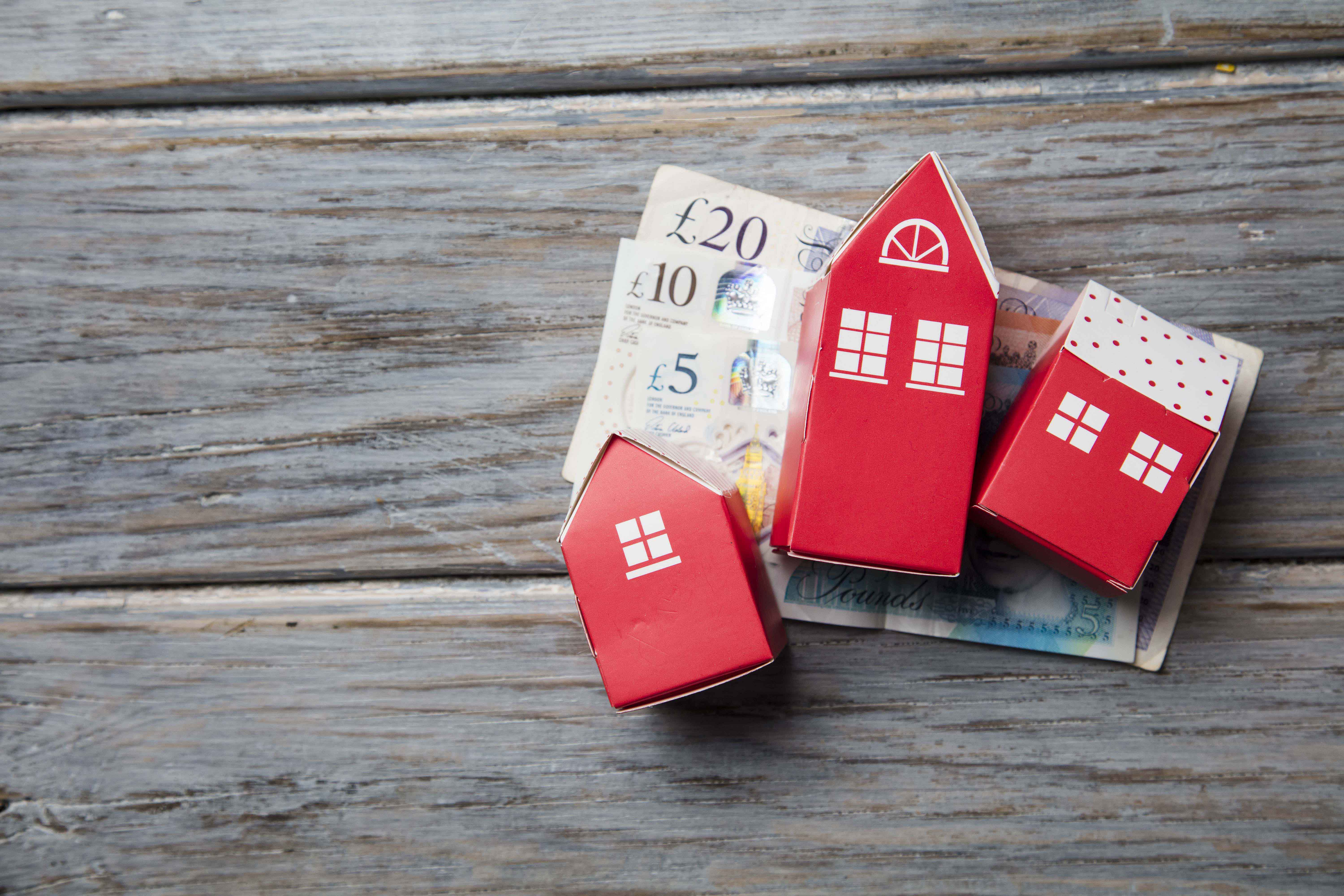 Housing cost. Paper toy house with British currency notes